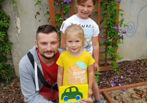 tata z córkami pozują do zdjęcia w ogrodzie przedszkolnym