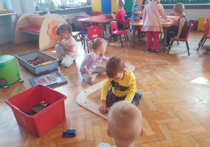 dzieci bawią na podłodze - budują drogę zdrewnianych klocków