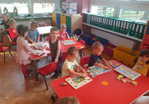 dzieci bawią się przy stolikach - dzieci układają drewniane układanki