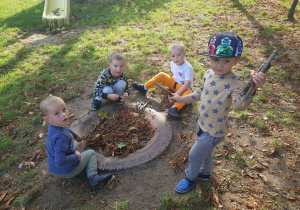 chłopcy w ogrodzie bawią się patykami i liśćmi