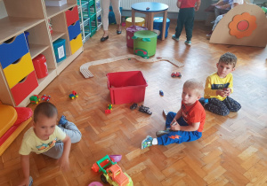 chłopcy bawią się autkami siedząc na podłodze