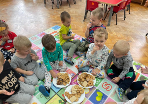 piknik w przedszkolu - chłopcy z grupy VII częstują się słodyczami siedząc na macie w sali