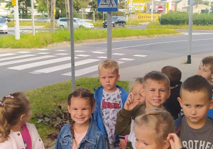 dzieci stoją na chodniku pod znakami drogowymi w pobliżu przejścia dla pieszych