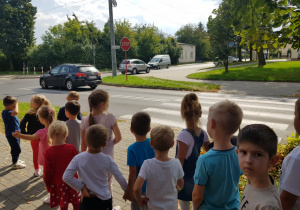 dzieci stoją przy skrzyżowaniu dróg i oglądają znak - stop