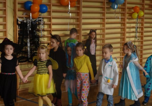 taniec: dzieci w strojach balowych trzymają się za ręce i idą w kole