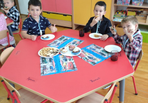 chłopcy siedzą przy stoliku i piknikują przy ciasteczkach