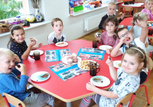 dzieci siedzą przy stoliku i piknikują przy ciasteczkach