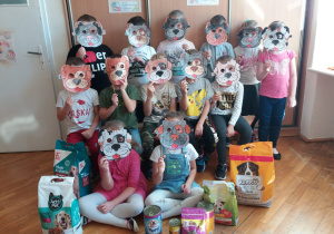 grupa dzieci z twarzami zakrytymi maskami piesków zamocowanymi na patyczku