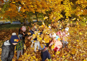 dzieci w parku rzucają kolorowymi liśćmi