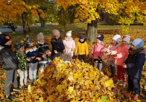 dzieci w parku stoją przy wielkiej górze kolorowych liści