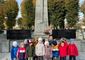 dzieci pod pomnikiem nieznanego żołnierza na cmentarzu