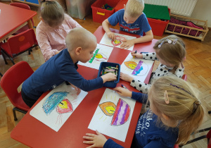dzieci przy stoliku kolorują znicze