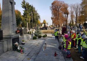 dzieci kładą na płycie pomnika doniczkę z kwiatami