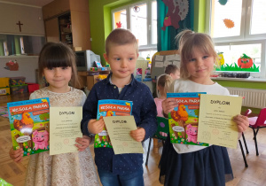 nagrodzona trójka dzieci z dyplomami i książkami