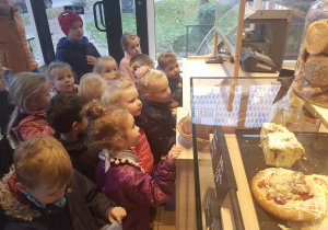 dzieci stoją w piekarni i oglądają różne rodzaje pieczywa