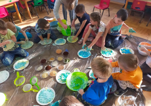 dzieci z pomocą mamy kolorują swoje ciasta na niebiesko