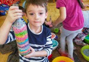 chłopiec pokazuje swoją kolorową butelkę