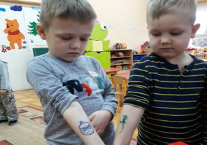 chłopcy pokazują tatuaże na ręce: pirat, zielona jaszczurka