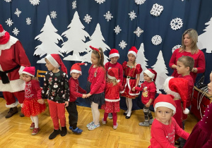 dzieci tańczą w kole z Mikołajem oraz parami