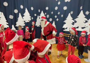 Mikołaj tańczy z dziećmi i trzyma je za ręce