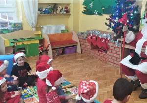 Mikołaj siedzi na krześle przed dziećmi i z nimi rozmawia