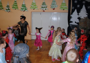 nauczycielka w czarnej, cekinowej sukience tańczy z dziećmi w kółku