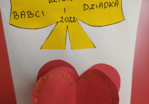 laurka z naklejonym czerwonym serduszkiem i żółtą kokardą z napisem "Dzień Babci i Dziadka 2022"