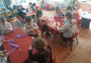 dzieci przy stolikach przygotowują kapelusz Marzanny z kolorowej bibuły