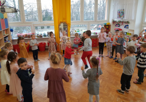 zabawa - dzieci stoją w kole i klaszczą w dłonie a w środku dziewczynka z chłopcem tańczą razem trzymając za kółko