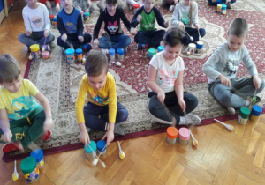 dzieci grają na bębenkach z puszek pałeczkami z korków i patyczków do szaszłyków