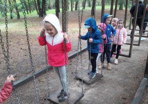 dzieci na torze przeszkód - dzieci chodzą po podestach w kształcie kwadratów podwieszonych na łańcuchach