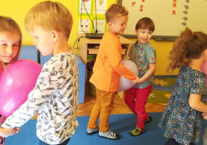 dzieci tańczą w parach a balonami umieszczonymi między brzuchami