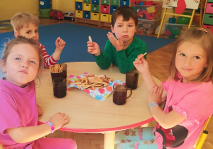 dzieci przy stolikach jedzą ciasteczka