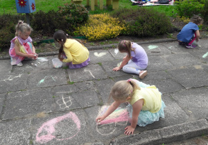 dzieci rysują kredą na płytach chodnikowych