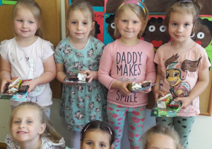 dzieci 4 letnie nagrodzone w konkursie plastycznym - stoją w sali przed tablicą z pracami plastycznymi, na których jest Murzynek Bambo