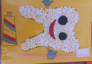 praca plastyczna - uśmiechnięty ząbek wyklejony styropianowymi kulkami trzyma szczoteczkę wykonaną ze słomki i białego , pociętego papieru a na dole strony narysowana kolorowa tubka pasty