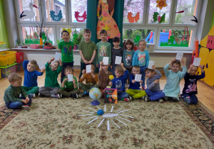 dzieci z grupy I siedzą przed globusem a w dłoniach trzymają napis z pojedyńczych liter Dzień Ziemi
