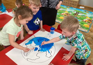 dzieci malują niebieską farbą kontur Ziemi