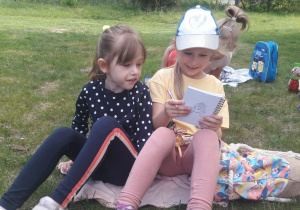 dziewczynki podczas pikniku na łące rysują w zeszycie