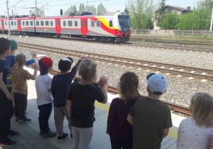 dzieci machają do maszynisty nadjeżdżającego pociągu