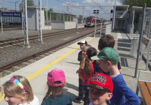 dzieci patrzą na pociąg stojący przy peronie oraz zachowanie ludzi
