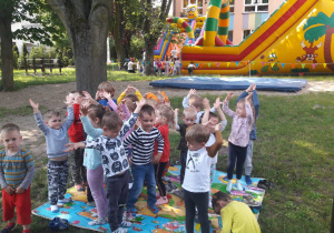 dzieci tańczą w ogrodzie przedszkolnym oczekując na zabawę na zjeżdżalniach