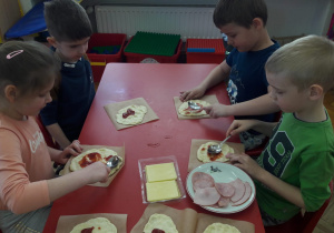dzieci smarują ketchupem ciasto na pizzę