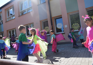 dzieci z grupy I tańczą na tarasie przedszkolnym w kostiumach kolorowych motyli