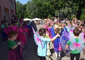 dzieci z grupy I tańczą na tarasie przedszkolnym w kostiumach kolorowych motyli przed rodzicami
