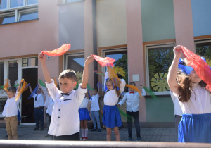 dzieci z grupy V tańczą na tarasie przedszkolnym z kolorowymi chustkami
