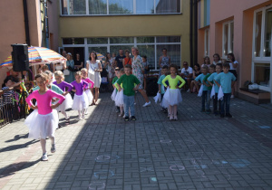 dzieci z grupy I ustawione w rzędach tańczą z białymi chustkami