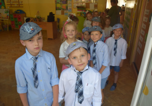 dzieci z grupy III stoją parami przed występem - chłopcy w niebieskich kaszkietach i krawatach a dziewczynki w białych bluzkach i różowych spódniczkach