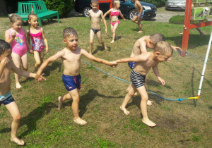 dzieci przed kurtyną wodną biegną trzymając się za ręce