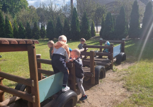 chłopcy bawią się w ogrodzie w wagonikach lokomotywy